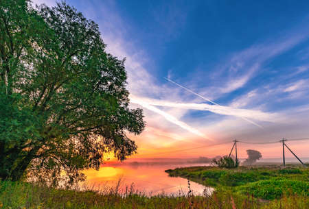 colorful calm dawn in the morning on the pond sun rays reflection in the waterの写真素材