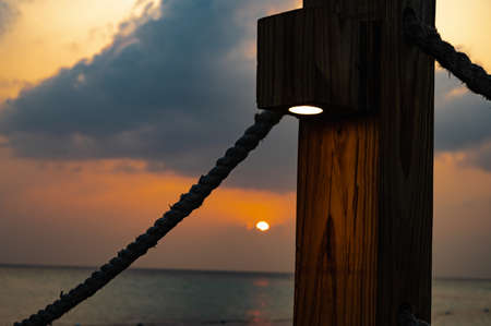 wooden bridge jetty in the sea illuminated at sunsetの写真素材
