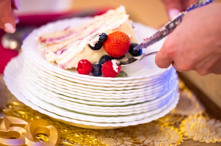woman cuts a birthday cake with fruits and berries close-up
