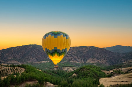 Hot air balloon above high mountain at sunset, filtered backgroundの写真素材