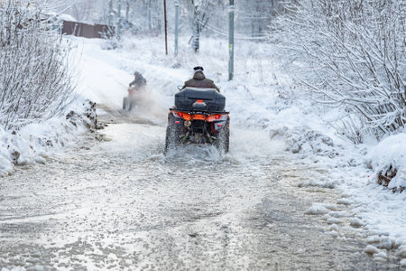 quad bike rides through deep puddles in the spring, breaking iceの写真素材