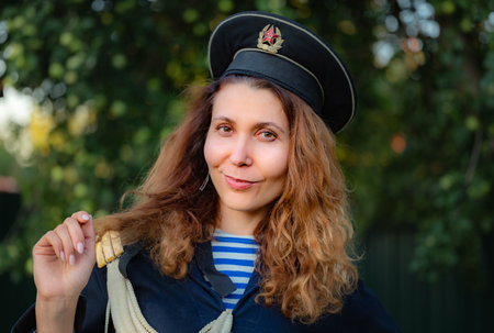 portrait of a young curly woman with red hair in a navy vest and capless capの写真素材