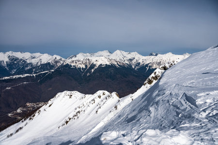 mountains with snowy off-piste slope and blue sunlit sky at winter. Caucasus Mountains,