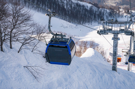 ski lift gondolas against blue sky over slope at ski resort on sunny winter dayの写真素材