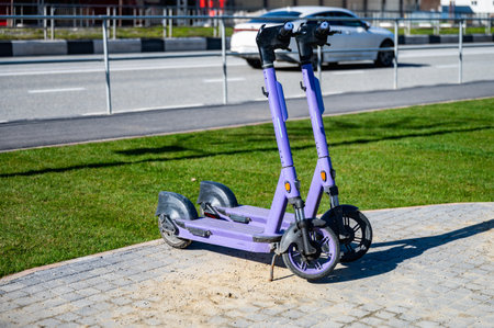 Two purple scooters are parked on a sidewalk. One is on the left and the other is on the rightの写真素材