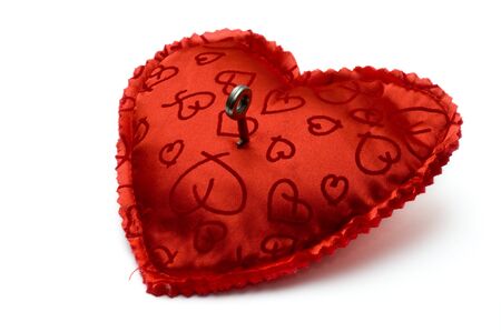 Small key opening a red heart shaped pillow isolated on whiteの写真素材