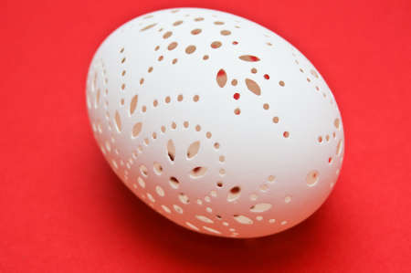 White pierced easter egg isolated on redの写真素材