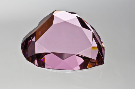 Pink colored crystal heart side view isolated on grey