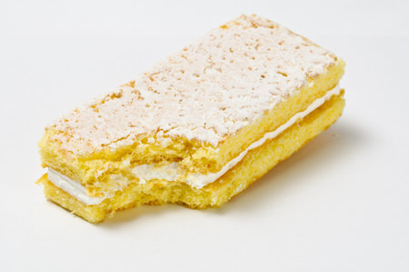 Lifted sponge cookie with skimming filling bite isolated on gray