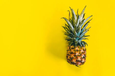 A fresh pineapple fruit on a yellow background with space for your textの写真素材