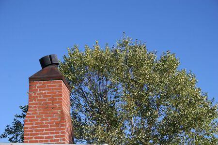 Brick Chimney in old building against tree and blue skyの写真素材