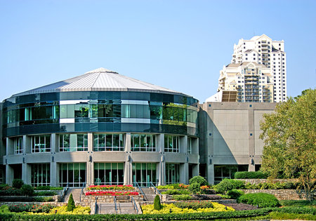 A short round office building next to a tall modern tower