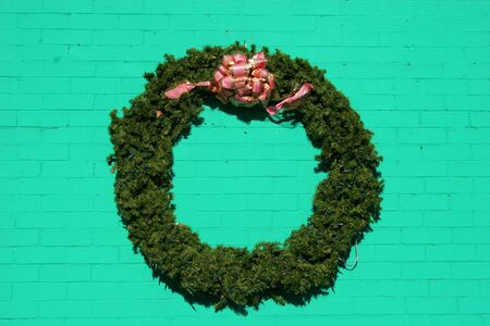 Christmas wreath hanging on green painted brick wallの写真素材