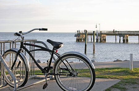 A lone bicycle in rack in front of pier at the beachの写真素材