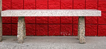 Empty concrete bench in front of red block wallの写真素材