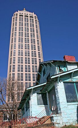 Modern skyscraper rising behind old condemned houseの写真素材
