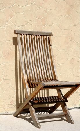 An empty wooden chair casting shadows on a wallの写真素材