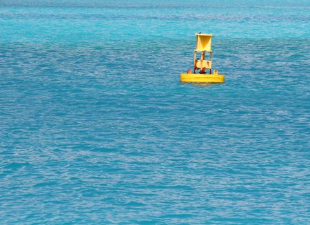 A bright yellow buoy in a blue seaの写真素材