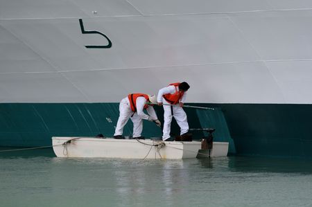Two workers painting the hull of a shipの写真素材