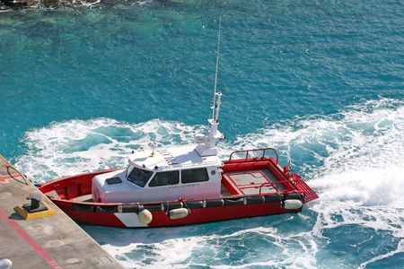 Red pilot boat cruising through aqua watersの写真素材