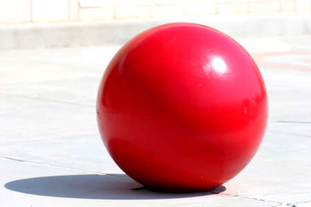 A large red concrete ball in front of a storeの写真素材