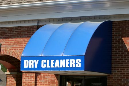 A bright blue canopy over a dry cleaners windowの写真素材