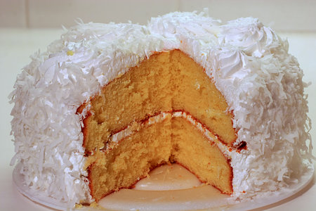 A fresh coconut cake sliced for servingの写真素材