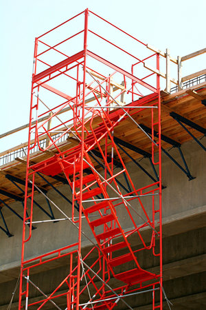 Steel orange stairs and scaffolding on a bridge construction