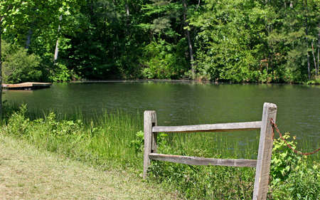 A section of split rail fence beside A peaceful lakeの写真素材