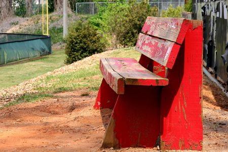 An old wooden bench with peeling red paintの写真素材