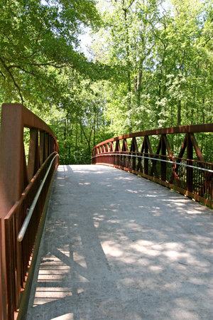 A wood, steel, and concrete bridge in the woodsの写真素材