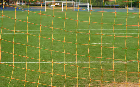 A soccer field as seen through the net of the goalの写真素材
