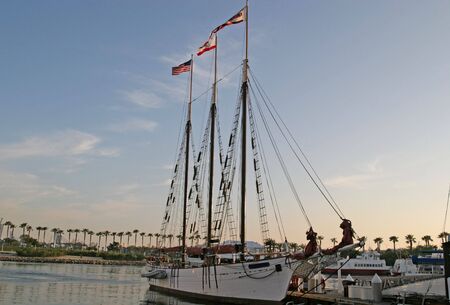 Three masts of a sailing vessel rising into the dawn skyの写真素材