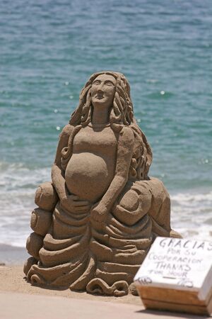 A sand sculpture of a pregnant woman on the beachの写真素材