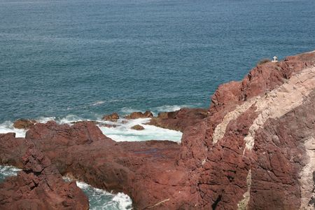 Rocky cliffs leading to sea with a cross at the edgeの写真素材