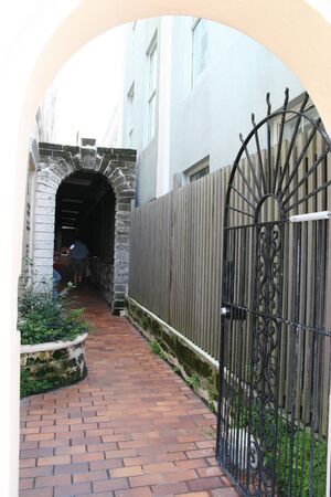An arched iron gate into a corridor to another archの写真素材