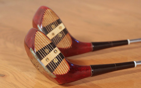 Two old golf clubs on a hardwood floorの写真素材