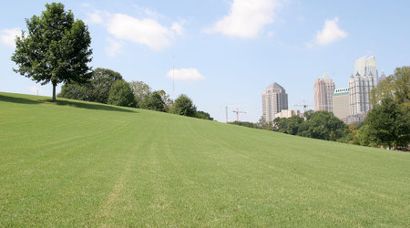 City skyline over a grassy hill and blue skyの写真素材