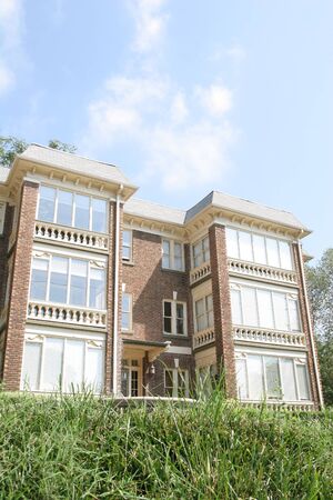 An old brick and glass apartment building on a grassy hillの写真素材