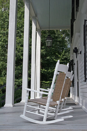 Old white rocking chairs on a colonial porch with white columnsの写真素材