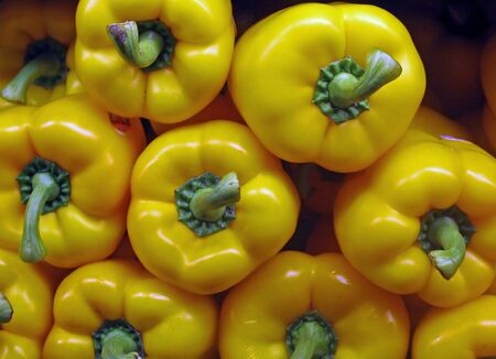 A display of yellow bell peppers in a vegetable marketの写真素材