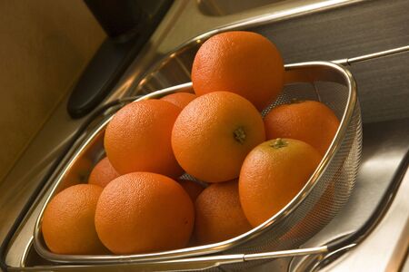 Artificial oranges in a strainer on a sinkの写真素材