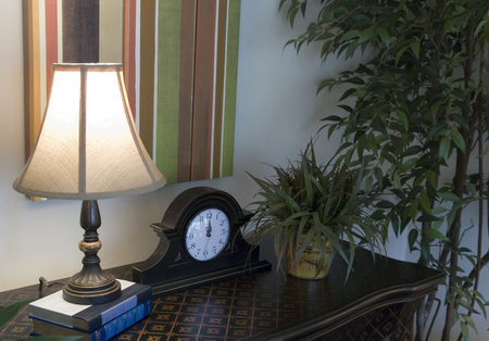An interior shot of a small table, clock, and lamp
