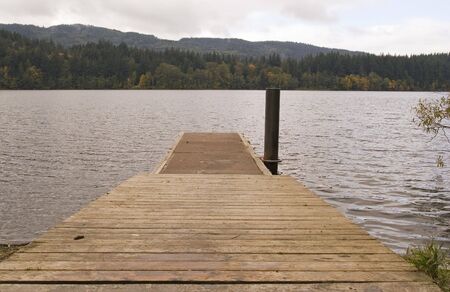A fishing pier extending into a placid lakeの写真素材