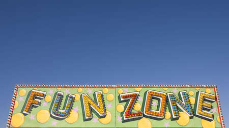 A colorful fun zone sign at a carnival against a blue skyの写真素材