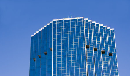 A blue glass office tower against a blue sky