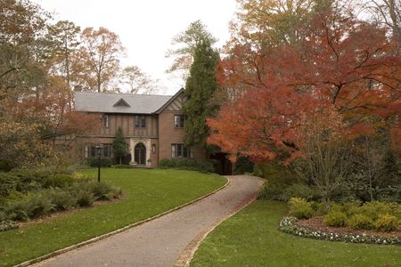 A nice old house in tudor style in the autumn with red leaves on treesの写真素材