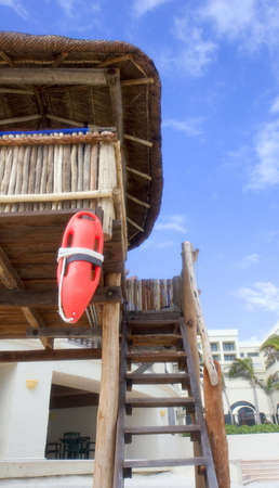 Steps up to a wooden bamboo and straw thatch lifeguard hut on the beach with orange floatの写真素材