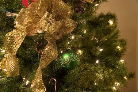 A christmas tree decorated with green ornaments and gold ribbonsの写真素材