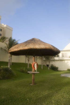 An orange life ring on a straw hut in the courtyard of a seaside resortの写真素材